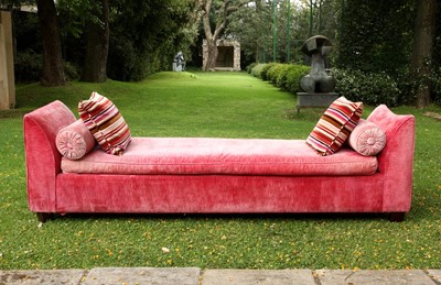 Lot 93 - An upholstered day bed covered in coral pink velour